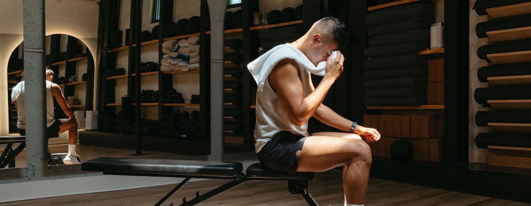 A man sitting on a bench in a gym.